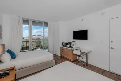 a bedroom with a bed and a desk with a television at 2 Bed 2 Bath at Beachwalk With Pool Gym Beach in Hallandale Beach