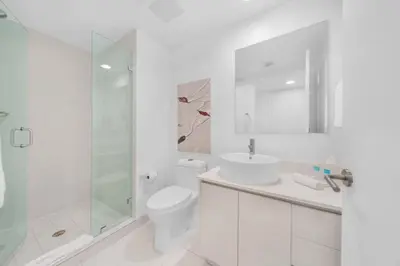 a white bathroom with a toilet and a glass shower at 2 Bed 2 Bath at Beachwalk With Pool Gym Beach in Hallandale Beach