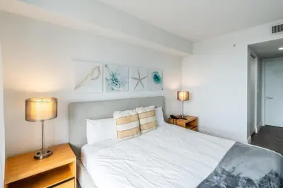 a bedroom with a bed with two lamps and two tables at 1 Bedroom w Kitchen on Beachwalk Beach &Pool &Gym in Hallandale Beach