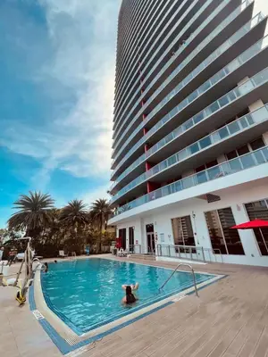 a person in a swimming pool next to a tall building at 2 Bed 2 Bath Full Equiped Beachwalk Pool Gym 22 in Hallandale Beach