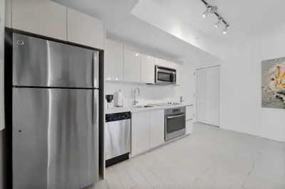 a large white kitchen with a stainless steel refrigerator at 1 Bed & Kitchen at Beachwalk Luxe Pool Gym Beach in Hallandale Beach