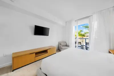 a white bedroom with a bed and a television at 2 Bed & 2 Bath at Beachwalk Pool Gym Beach on 19th in Hallandale Beach