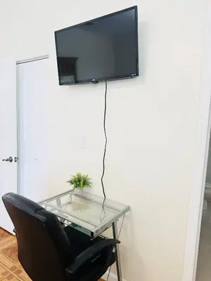 a glass table with a chair and a tv on a wall at Lujosa Y Acogedora Casa En Miami! in Tamiami