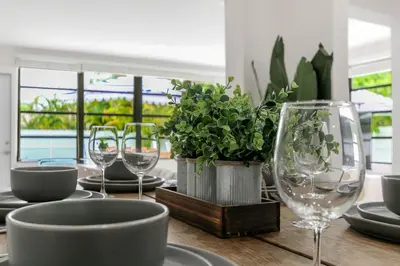 a wooden table with glasses and plates and plants on it at Charming 4BR Oasis with Saltwater Pool and Parking in North Miami