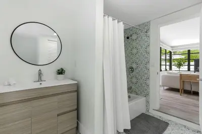 a bathroom with a sink and a mirror and a tub at Charming 4BR Oasis with Saltwater Pool and Parking in North Miami