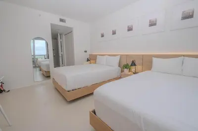 two beds in a white room with a mirror at Studio Luxury Ocean Views Apt in Hallandale Beach in Hallandale Beach