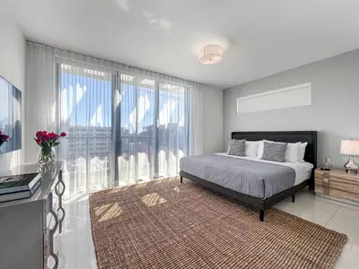 a bedroom with a bed and a large window at Bay Breeze Premium Apartments by Eskape Collection in Miami Beach