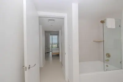 a white bathroom with a walk in shower and a hallway at 2B 2B Luxury Ocean Views Apt in Hallandale Beach in Hallandale Beach
