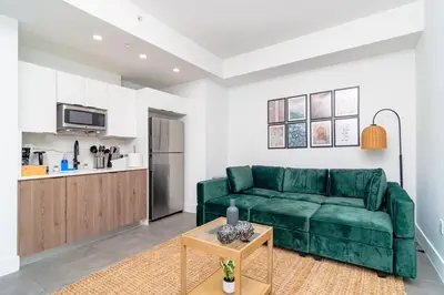 a living room with a green couch and a kitchen at Urban Oasis in Miami Close to Bayside and Brickell with Free Parking in Miami