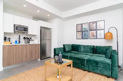 a living room with a green couch and a kitchen at Urban Oasis in Miami Close to Bayside and Brickell with Free Parking in Miami