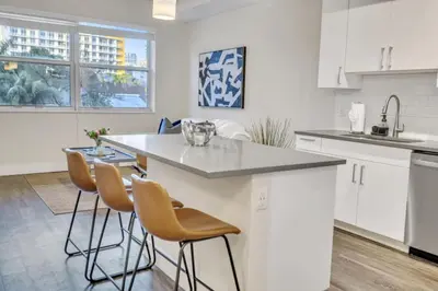 a kitchen with white cabinets and a island with bar stools at Trendy One Bedroom Getaway Steps from Biscayne in Miami
