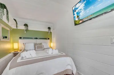 a bedroom with a bed with a tv on the wall at Casa Del Sol Cozy 2br Retreat 10 Mins To Beach in Miami