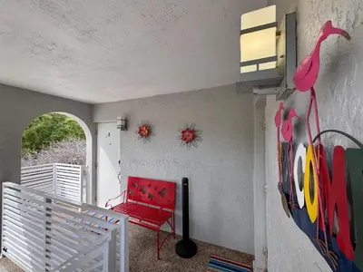 a red chair on a balcony with a red bird on the wall at Stylish 2 Bedrooms Apartment by Miami Airport in Miami