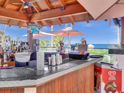 a woman sitting at a bar with an umbrella at Lovely 2BR condo with Resort Access, Gym and Pool 1608 in Miami Beach