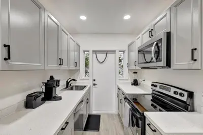 a white kitchen with a sink and a microwave at Banyan St. 1BR 1BA off Las Olas - Steps to Beach in Fort Lauderdale
