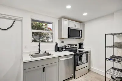 a white kitchen with a sink and a microwave at Banyan St 2BR 1BA off Las Olas- Steps to Beach unit 4 in Fort Lauderdale