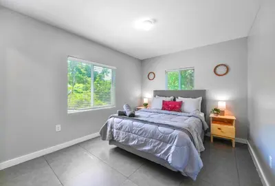 a bedroom with a large bed and two windows at Comfy & Spacious Duplex w Top Amenities! in Miami