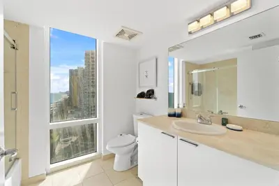 a bathroom with a sink and a toilet and a window at Luxurious 2BD Condo with Direct Ocean Front & Resort Pool in Sunny Isles in Sunny Isles Beach