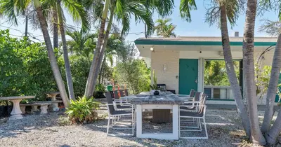 a table and chairs in front of a house with palm trees at Beachside Studio in Hollywood