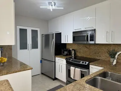 a kitchen with white cabinets and a stainless steel refrigerator at Urban Luxe Aventura 22 Retreat in Aventura