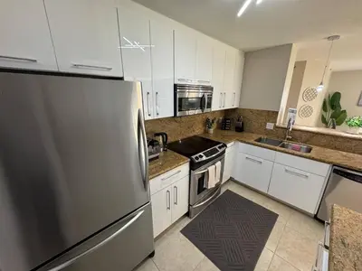 a kitchen with white cabinets and a stainless steel refrigerator at Urban Luxe Aventura 22 Retreat in Aventura