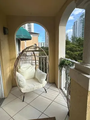 a rattan chair on a balcony with an archway at Urban Luxe Aventura 22 Retreat in Aventura