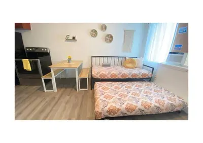 two beds in a room with a table and a kitchen at Cozy Place Near Design District - 2 in Miami