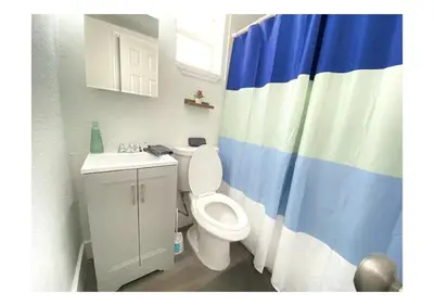 a bathroom with a toilet and a blue and white shower curtain at Cozy Place Near Design District - 2 in Miami