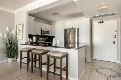 a kitchen with a counter with stools and a refrigerator at Miami apartamento sobre la playa con estacionamiento gratuito in Miami Beach