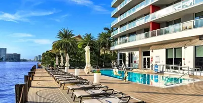 a row of chaise lounge chairs next to a swimming pool at Luxury Apt with Ocean View in Hallandale in Hallandale Beach