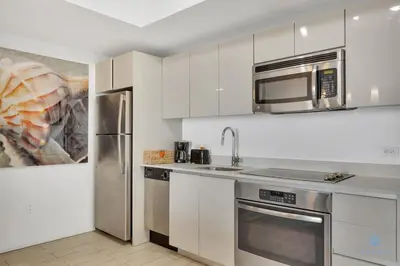 a kitchen with white cabinets and stainless steel appliances at Unique 2BR Apartment Gym & Pool in Hallandale Beach
