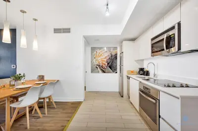 a kitchen with white cabinets and a table and chairs at 1BR Apartment with Balcony-Near Beach in Hallandale Beach
