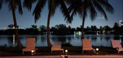 a group of chairs and palm trees in front of a lake at The Miami Enchanted Lake House in Ojus
