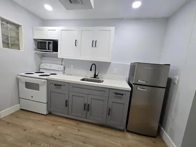 a kitchen with white cabinets and a stainless steel refrigerator at Miami Urban Oasis - B in Miami