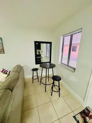 a living room with a couch and a table and two stools at Apartment in Hollywood close to shops & beach 108 in Hollywood