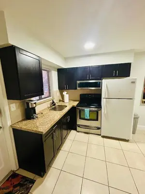 a kitchen with black cabinets and a white refrigerator at Apartment in Hollywood close to shops & beach 108 in Hollywood