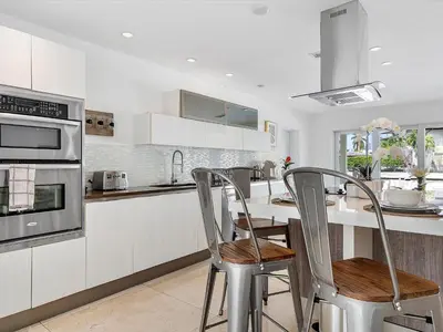 a kitchen with white cabinets and a table with chairs at luxury house by the water in Eastern Shores