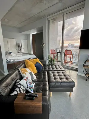 a living room with a leather couch and a bed at Luxury Loft 270 views, Rooftop Pool, Parking in Miami