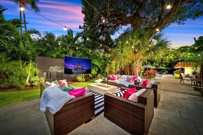 a patio with couches and a tv in a yard at Beach Estate Las Olas Beach Best Location in Fort Lauderdale