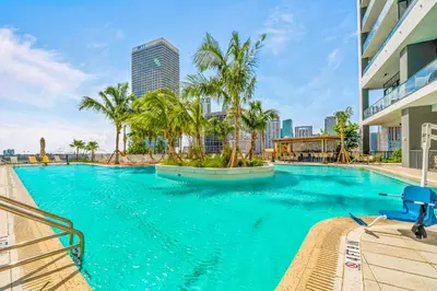 a large swimming pool with palm trees in a city at On The 49th Floor! Condo on Highest & Free Parking in Miami