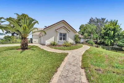 a house with a palm tree and a walkway at The Grand Luxe 8BR Villa w POOL and basketball in Pembroke Pines