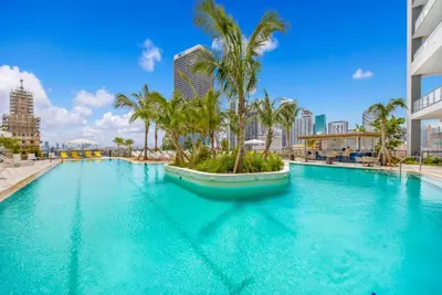 a large swimming pool with palm trees in a city at Stylish Downtown 1-BD Condo in Miami
