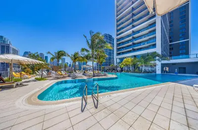 a swimming pool with palm trees and a tall building at Luxury Studio in DTW Miami with City Views in Miami