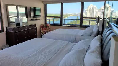 a bedroom with two beds and a tv and windows at Alexander 1420 in Miami Beach