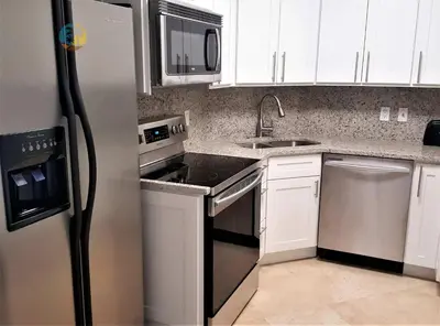 a kitchen with white cabinets and a stainless steel refrigerator at Alexander 510 in Miami Beach