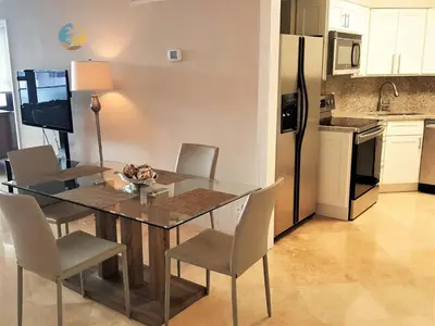 a kitchen with a dining room table with chairs and a refrigerator at Alexander 510 in Miami Beach