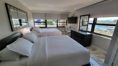 a bedroom with two beds and a television and windows at Alexander 521 in Miami Beach