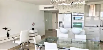 a dining room with a glass table and white chairs at Alexander 802 in Miami Beach