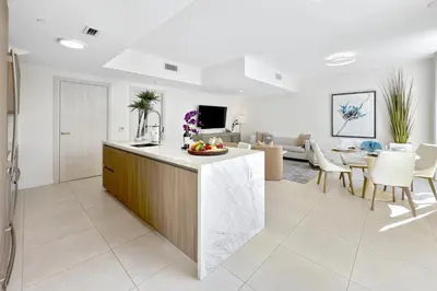 a kitchen and living room with a counter and a table at Tiffany Tides - Resort-Style Beach Townhome - Gym, Rooftop Pool and Sauna in Fort Lauderdale