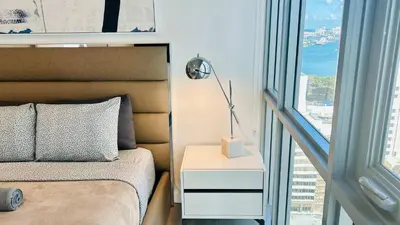 a bed with a lamp on a night stand next to a window at Rare Corner Unit Private Terrace & Sunset Views in Miami